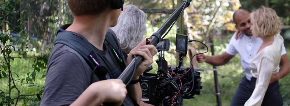Behind-the-scenes photos of July Janssen on movie sets. Features images with crew members, equipment, director, gaffer, best boy, and DOP
