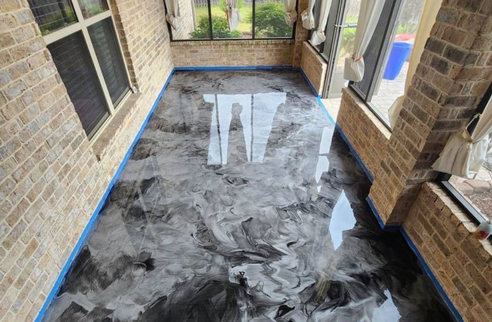 Marble-pattern epoxy floor in a screened porch, bordered with blue tape and brick walls