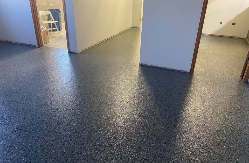 Empty room with speckled dark flooring, white walls, and open doorways leading to adjoining rooms
