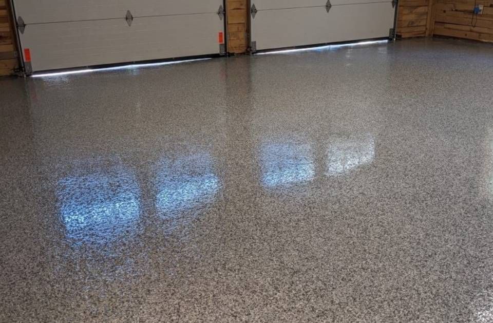 Empty garage with glossy speckled epoxy floor and closed doors reflected on the surface