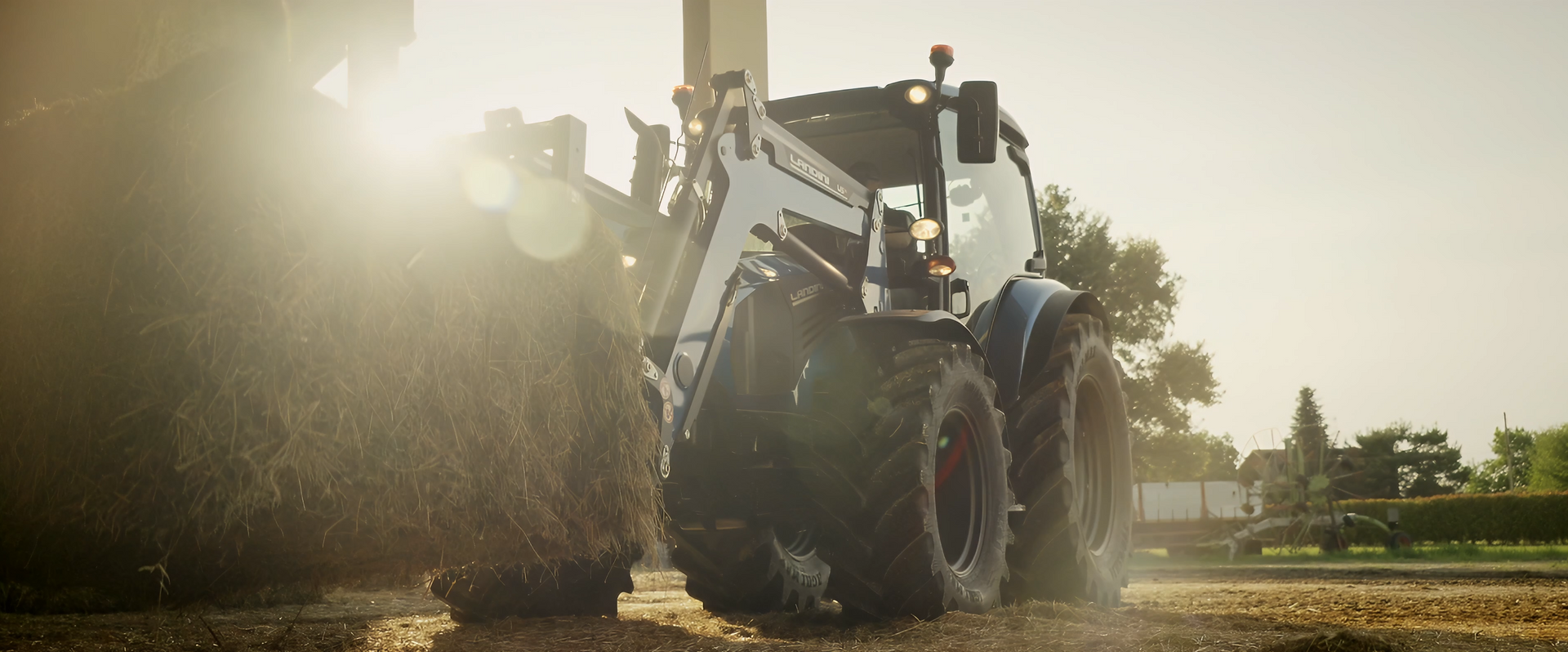 Un trattore attraversa un campo, con il sole che splende dietro di lui.