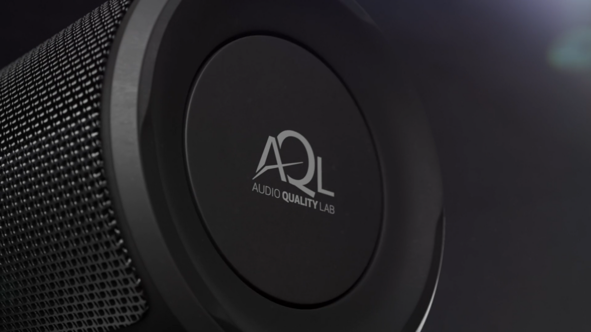 Close-up of a black speaker with a circular logo reading 