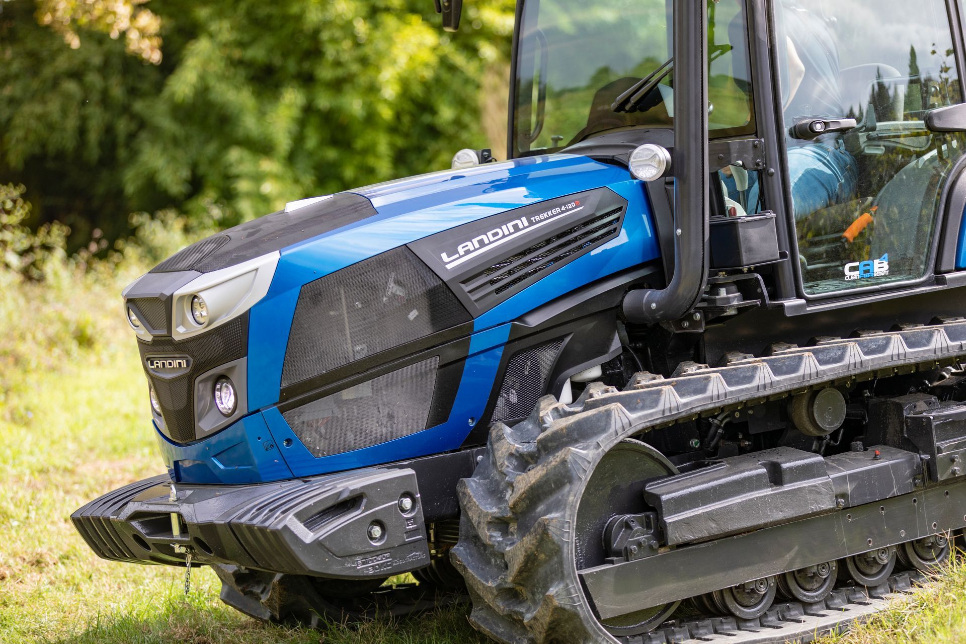 Blue Landini tractor with tracks, in a grassy field.