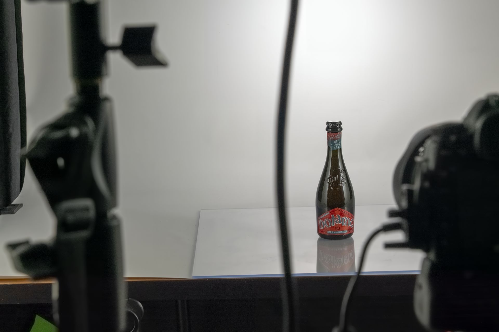 Una bottiglia di birra su un tavolo con uno sfondo bianco, un set fotografico con macchina fotografica e luci.