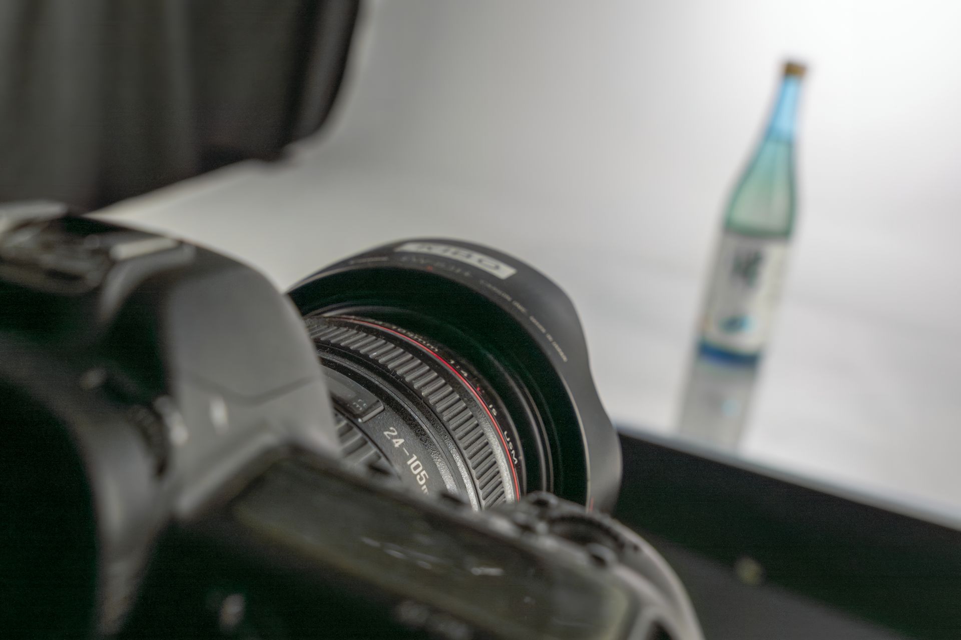 L'obiettivo della telecamera è puntato su una bottiglia d'acqua, posta su uno sfondo luminoso.