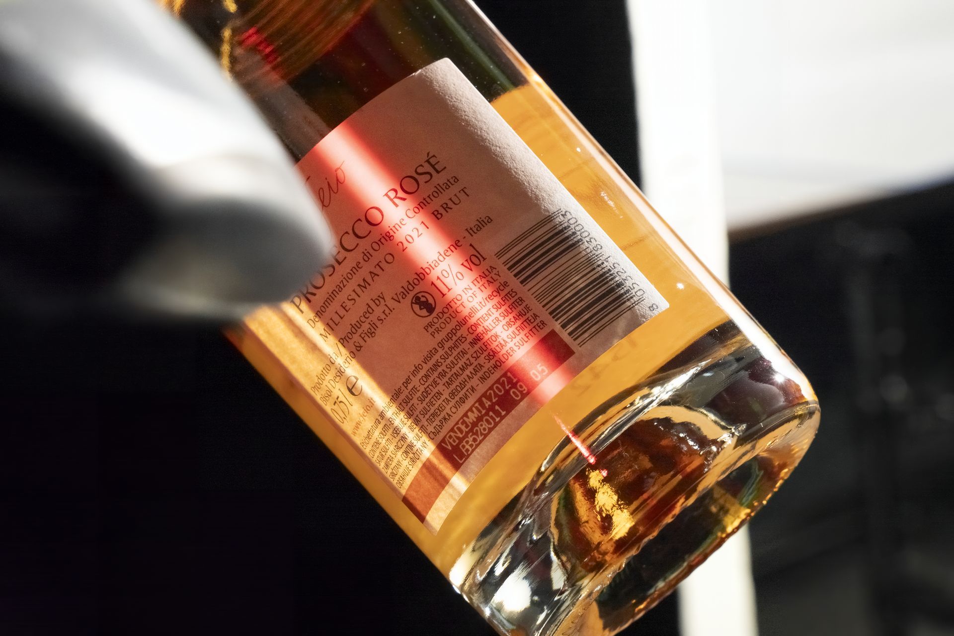 Bottiglia di vino rosato versata, con etichetta con testo e codice a barre.