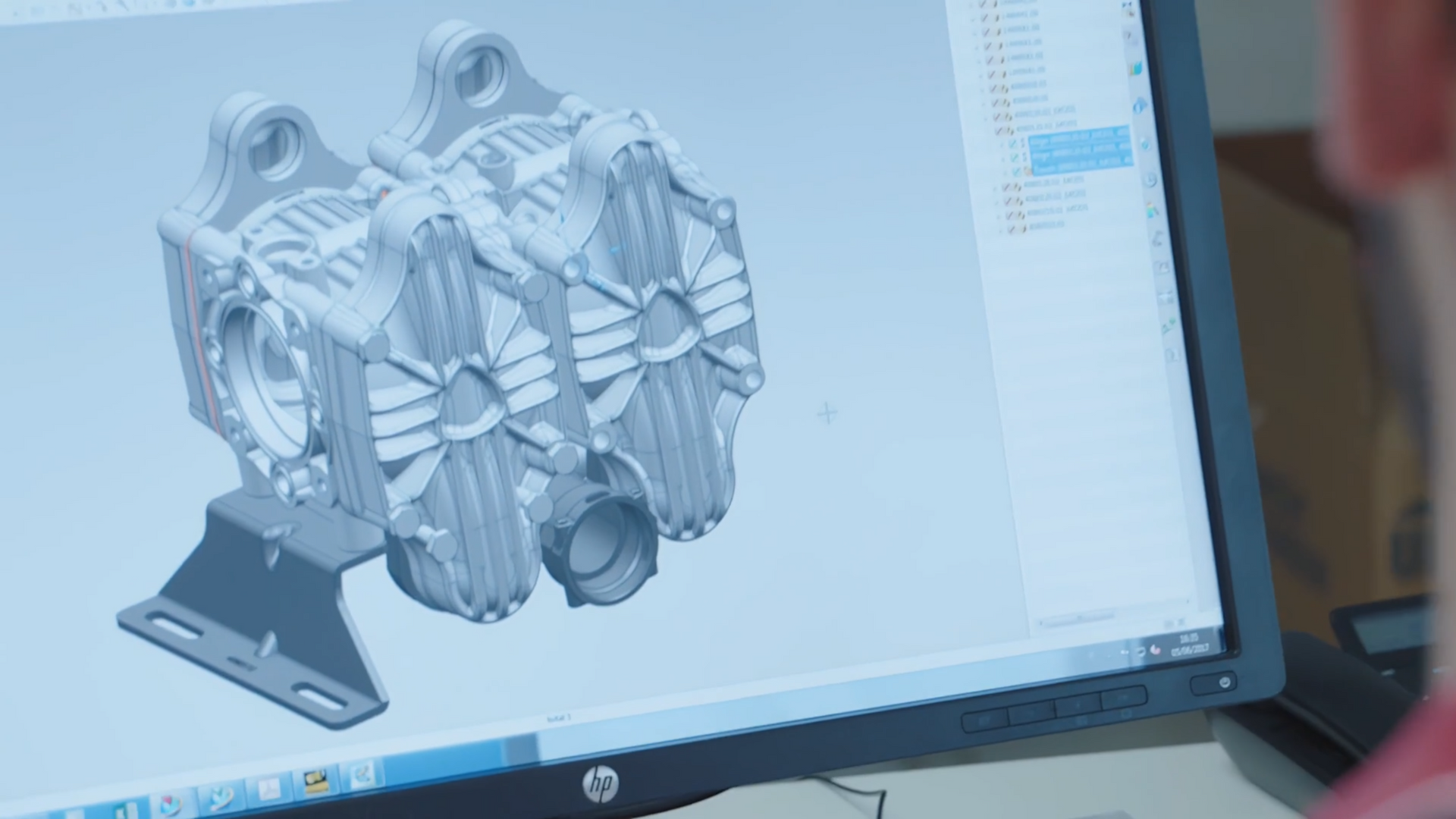 Rendering CAD di una parte meccanica complessa sullo schermo di un computer, visualizzato da una persona.