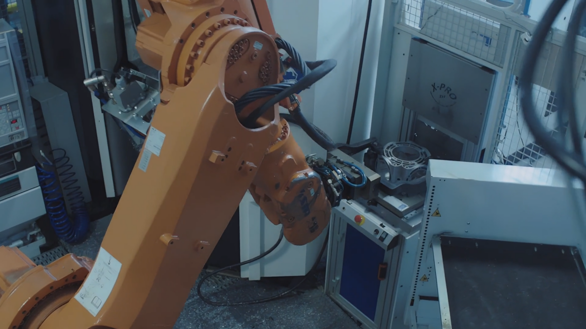 Braccio robotico industriale arancione al lavoro in una fabbrica.