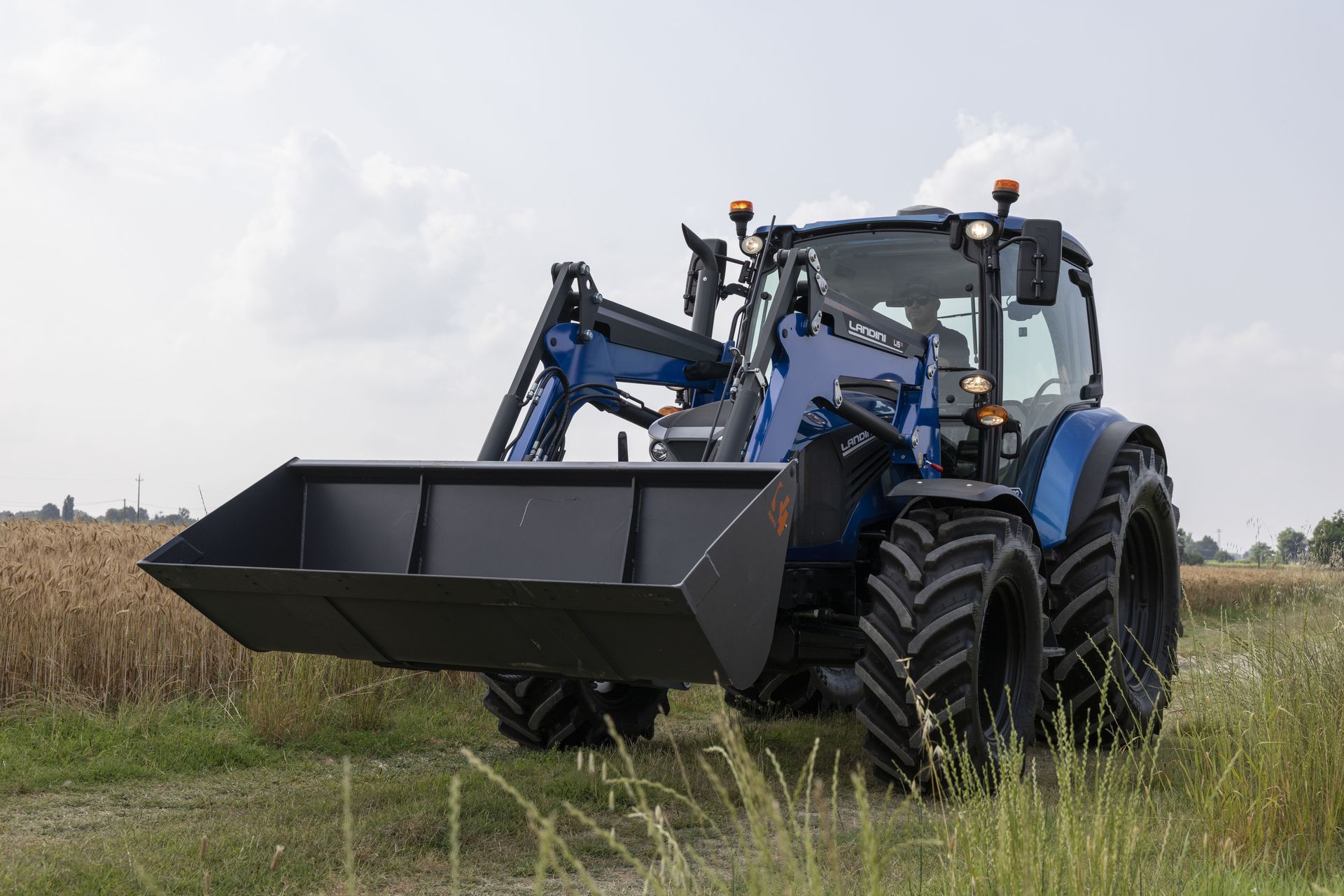 Trattore blu con caricatore frontale in un campo.