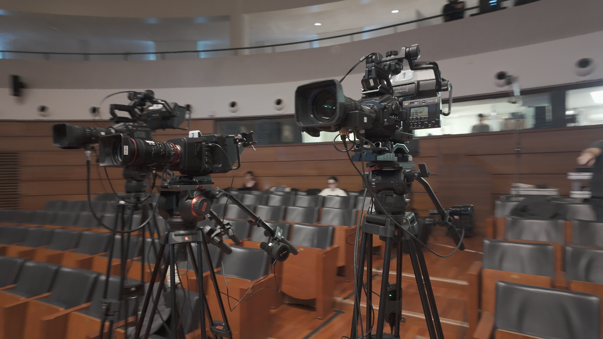Tre telecamere su treppiedi in un auditorium vuoto.