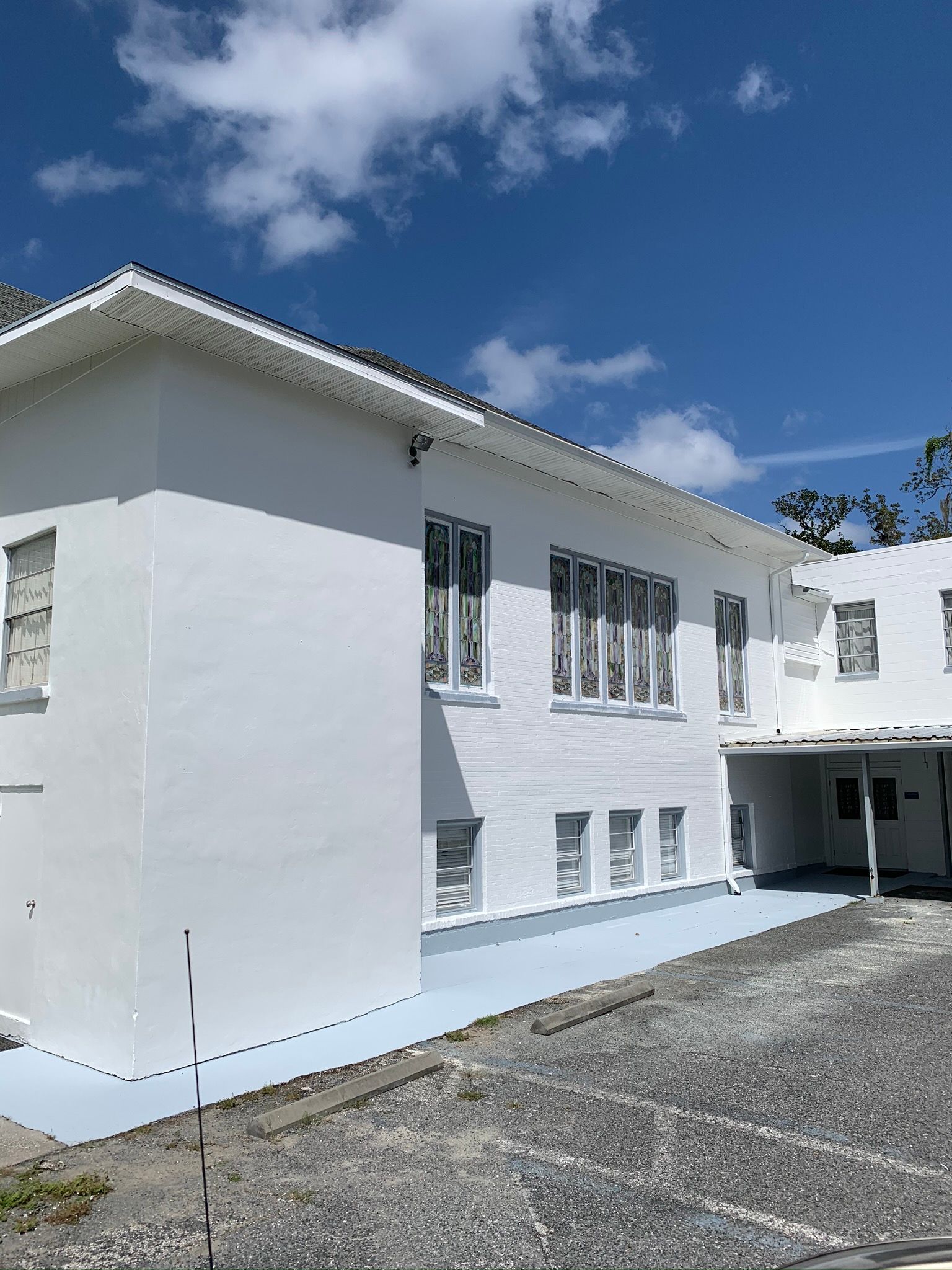 White two-story building with white windows and a gravel driveway under a blue sky.
