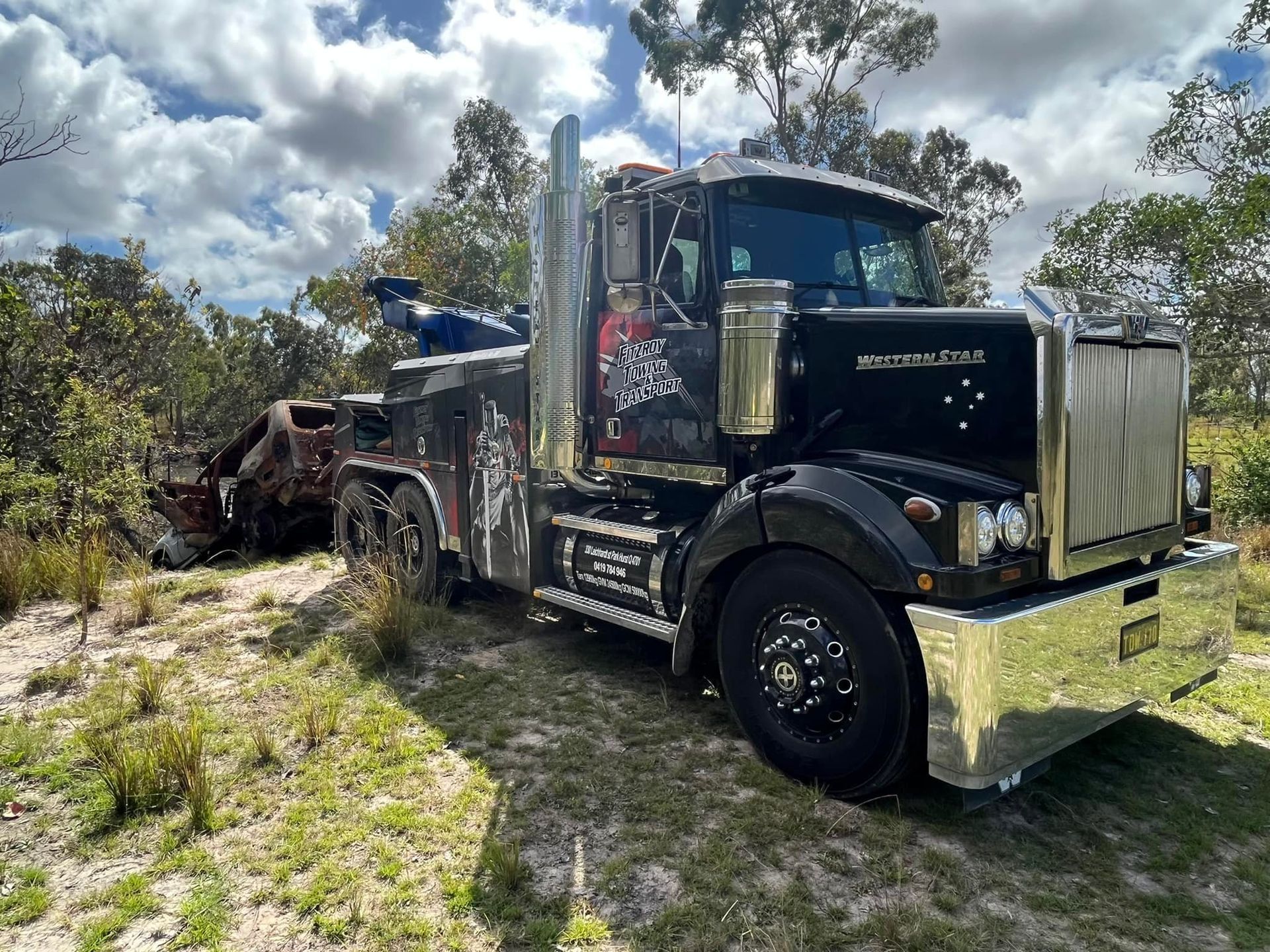 Black Tow Truck on Grass With a Damaged Vehicle — Fitzroy Towing & Transport in Biloela, QLD