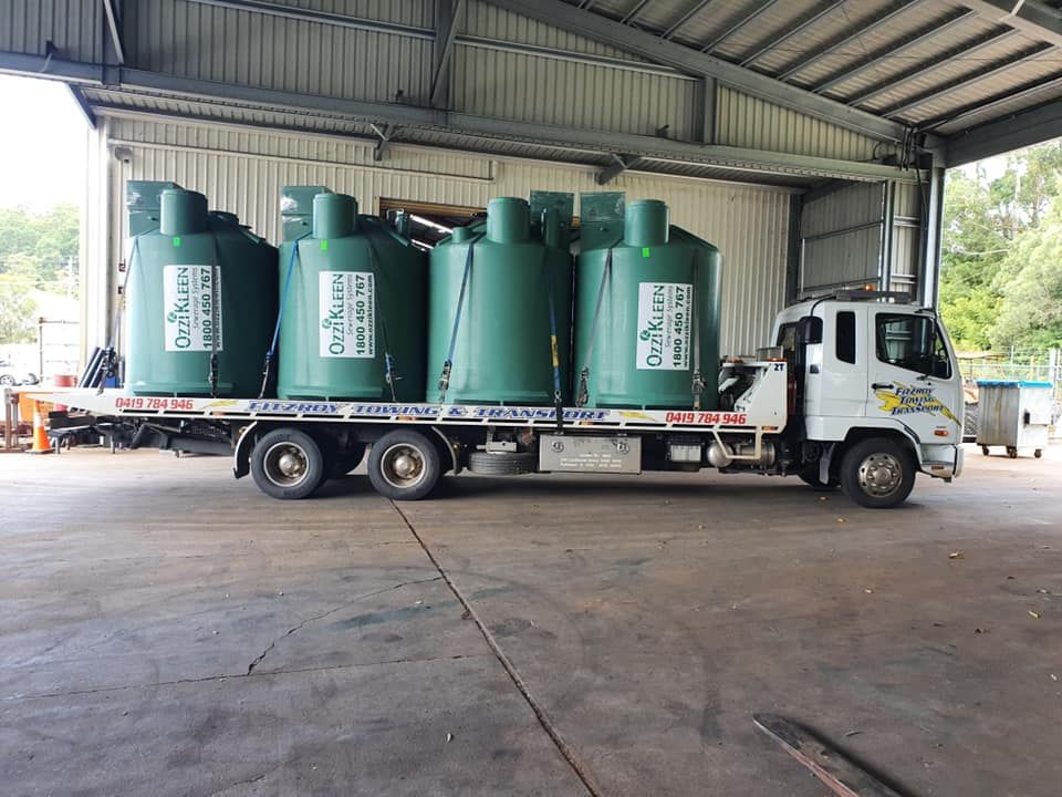 Truck Bed Loaded With Green Cylindrical Tanks Inside a Warehouse — Fitzroy Towing & Transport in Biloela, QLD