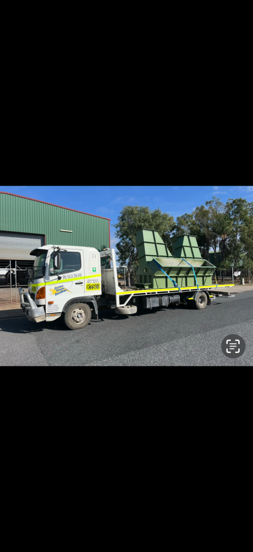 Truck carrying stacked green crates, parked on asphalt near a green building.— Fitzroy Towing & Transport in Parkhurst, QLD