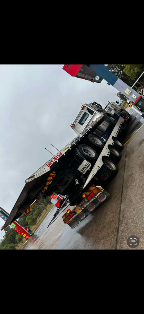 A large truck on the side of a road, possibly damaged, under an overcast sky.