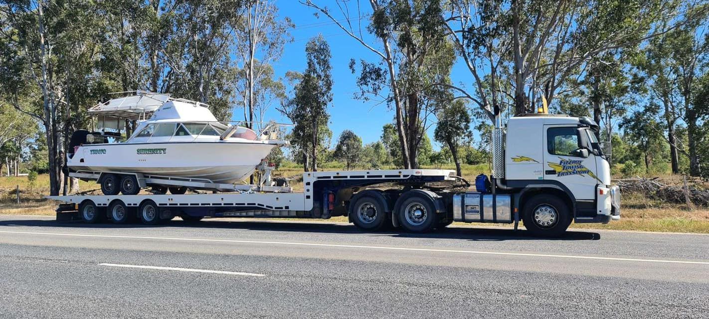 Truck Towing a White Boat on a Trailer, Driving on a Road — Fitzroy Towing & Transport in Emerald, QLD