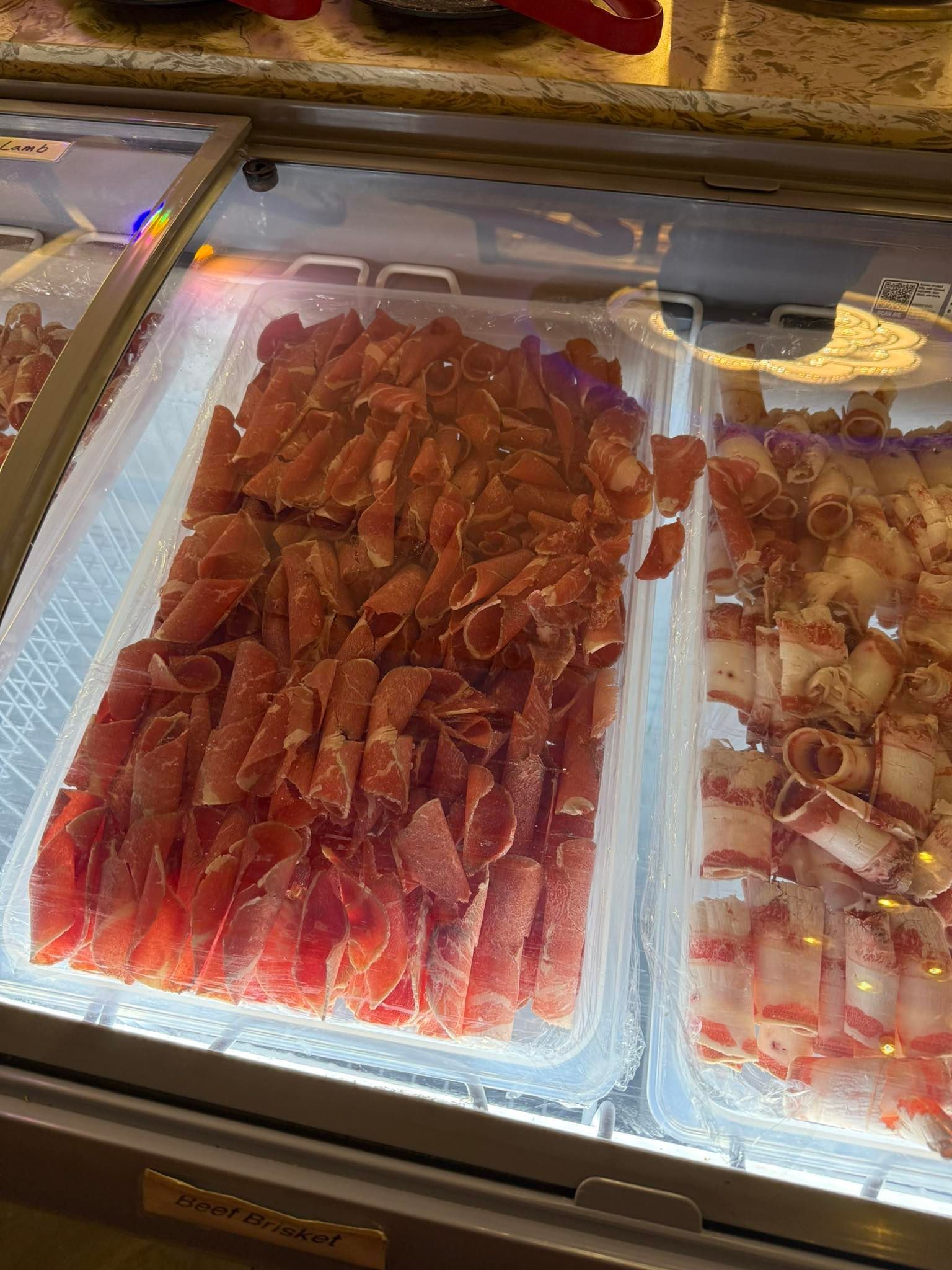 Seafood counter with trays of red crab legs and sliced octopus on ice