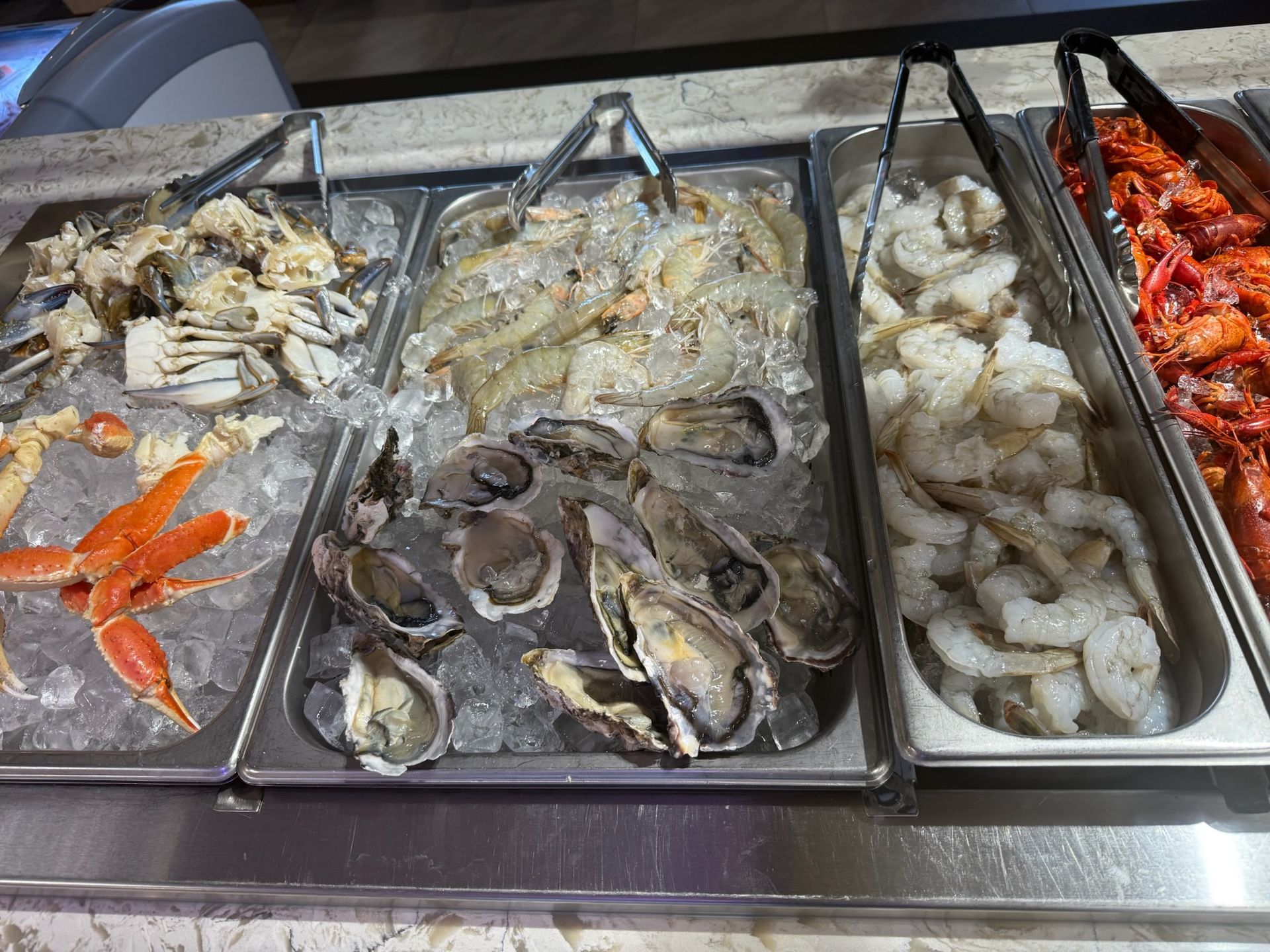 Seafood buffet trays with crab, oysters, shrimp, and grilled red fish on ice