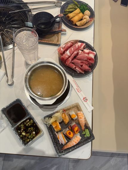 Sushi meal on a white table with soup, dipping sauces, chopsticks, and several small plates of sushi and sashimi