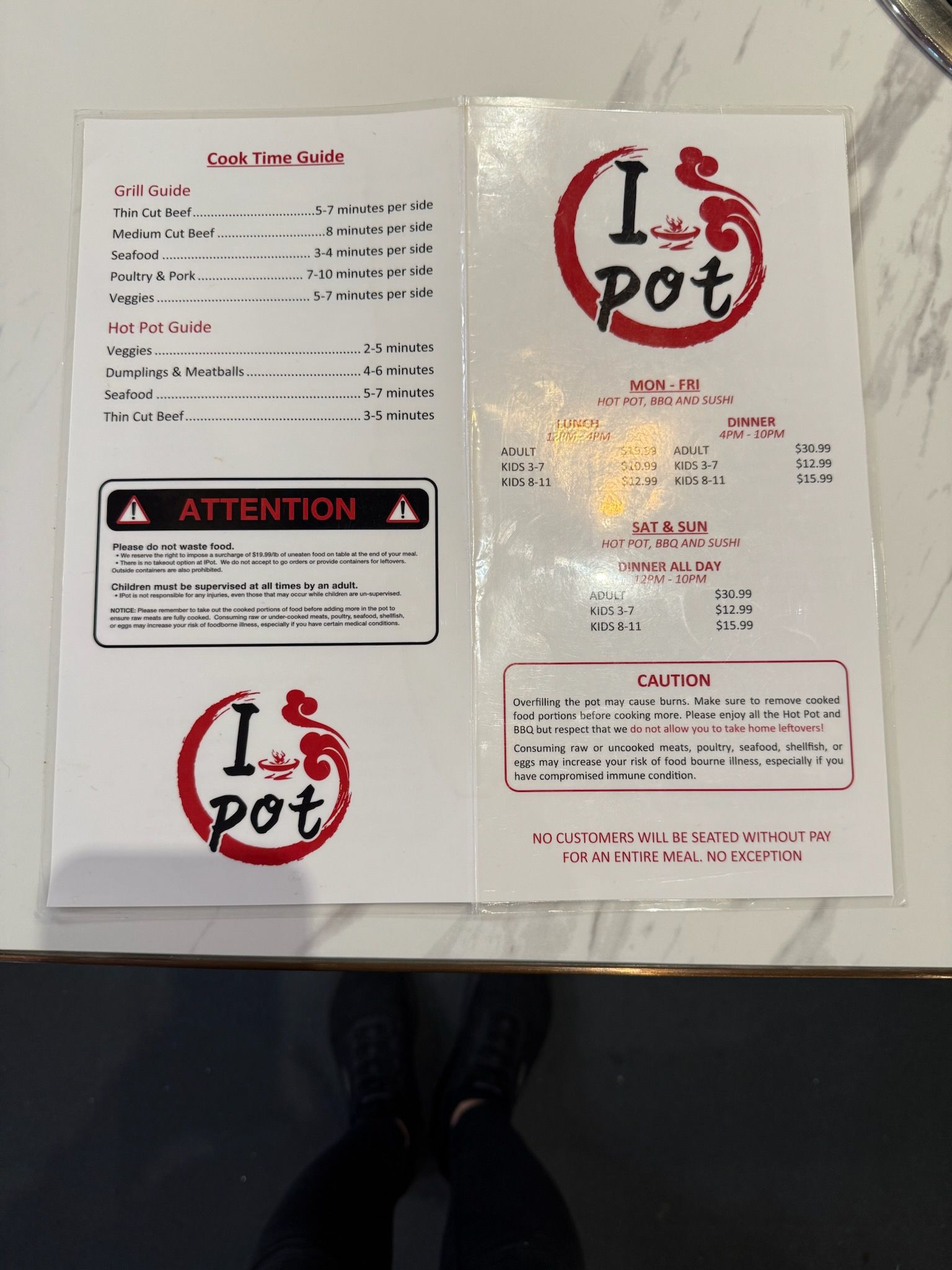 Restaurant menu and warning sign for “I Pot” on a white table, with red-and-black text.