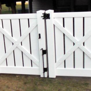 White picket fence with gate, black hinges, and latch, outdoors.