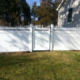 Tan vinyl fence with black hinges and latches, outdoor setting.