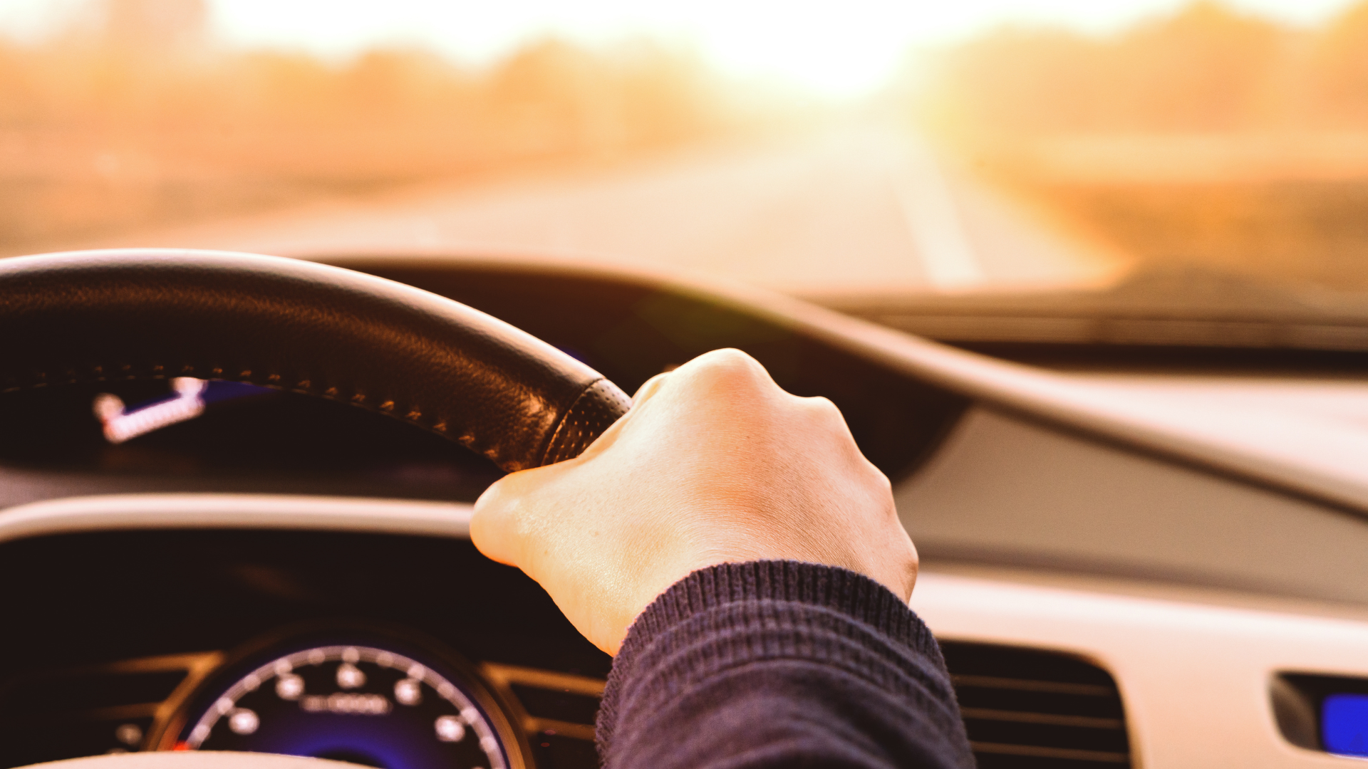 A person is driving a car with their hand on the steering wheel.