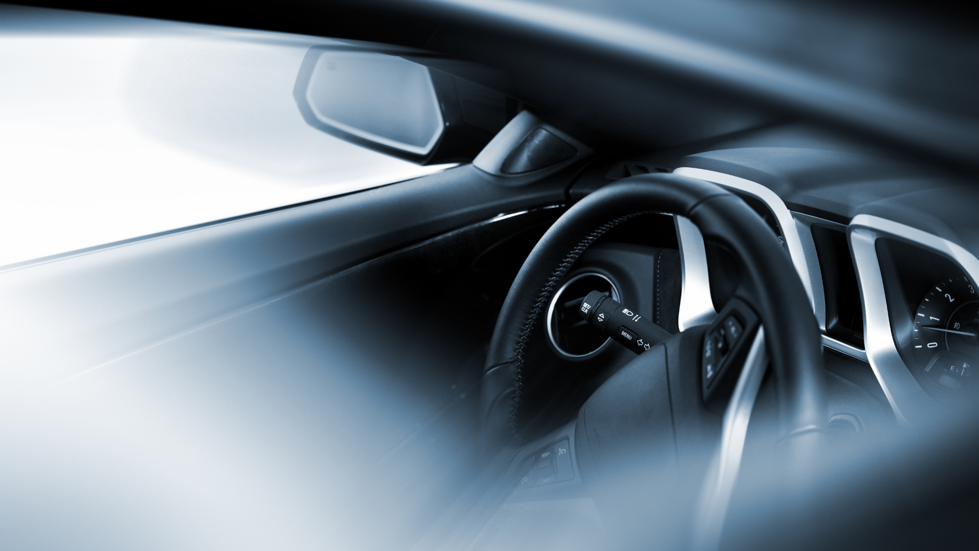 The inside of a car with a steering wheel and rear view mirror