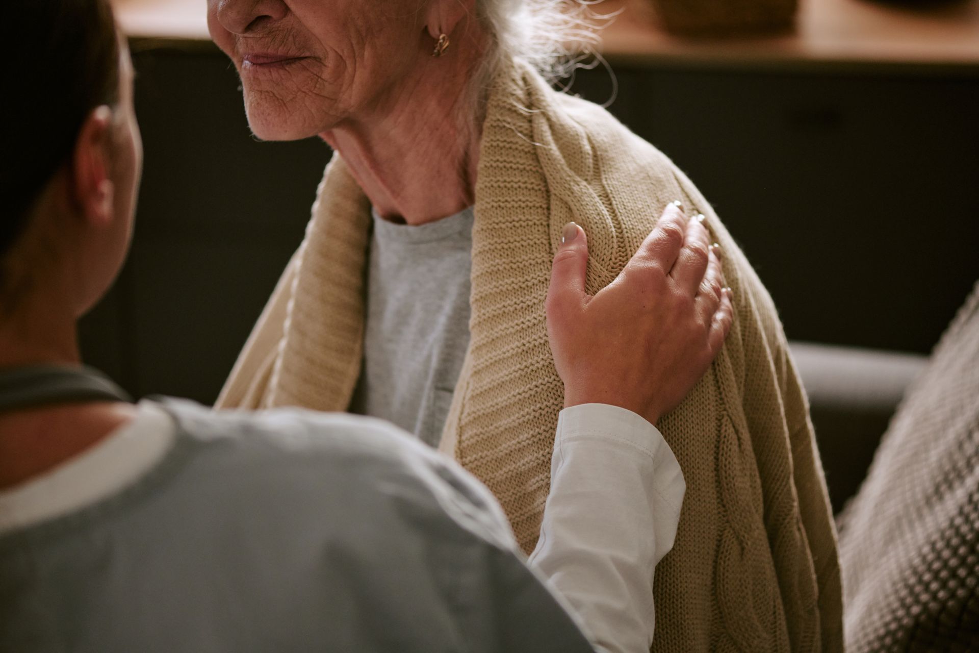 Person in a white shirt comforting an elderly person wearing a beige shawl