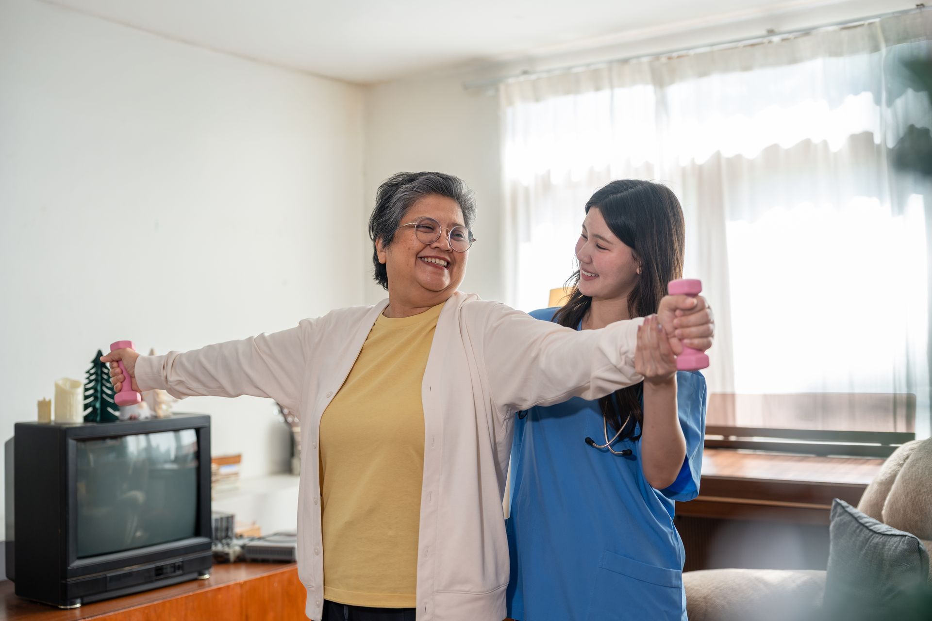 Two people smiling and dancing in a bright living room, one holding a pink shaker-like object.