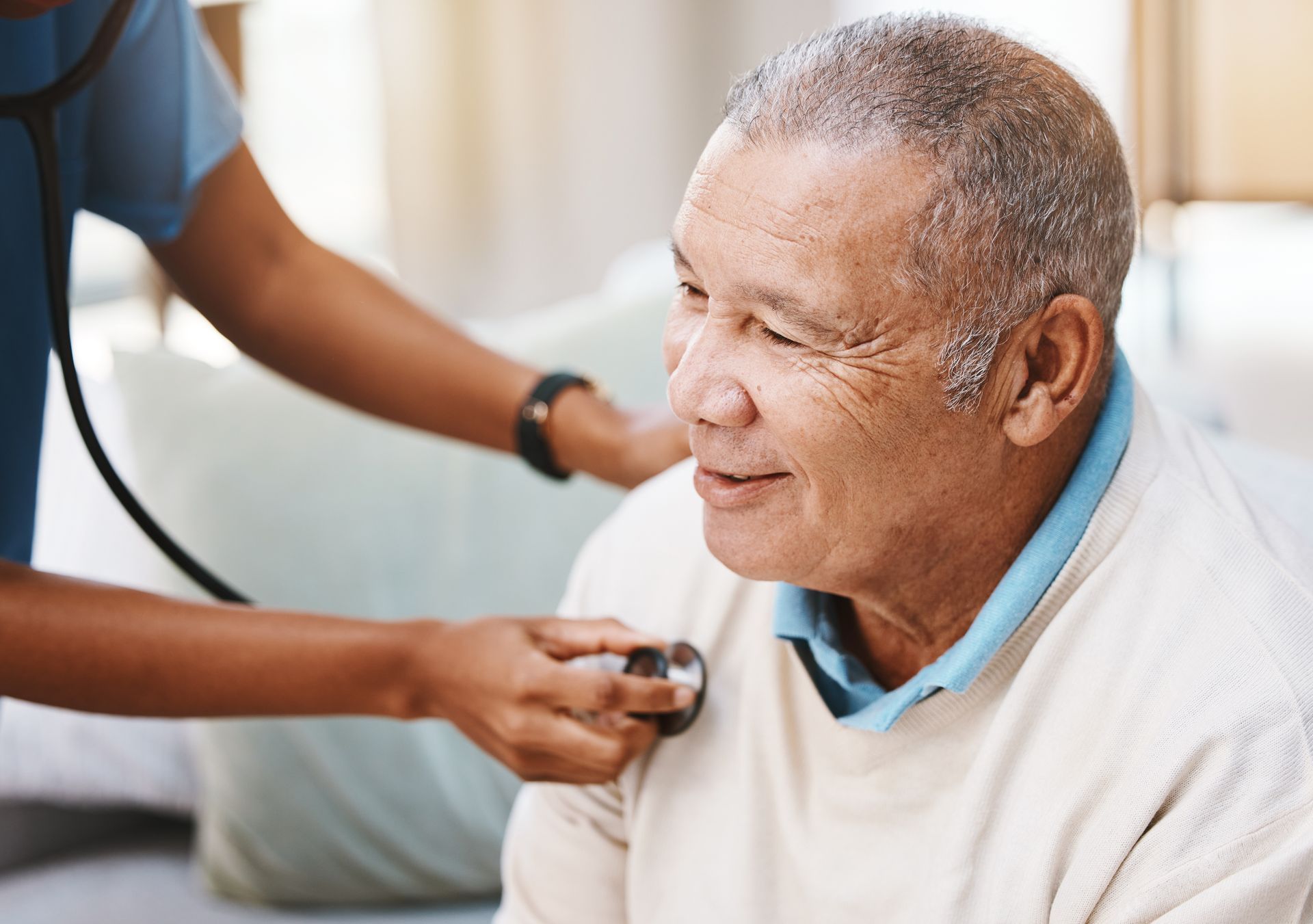 Nurse checking a seated patient’s chest with a stethoscope in a bright clinic room