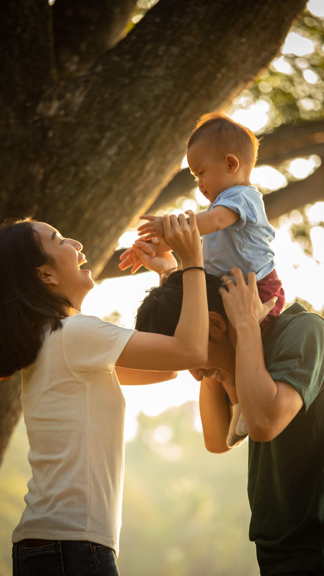 A man and woman are holding a baby on their shoulders.