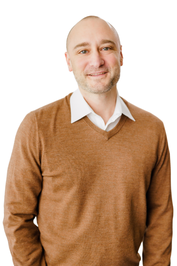 D.Rowe wearing a brown sweater and a white shirt.