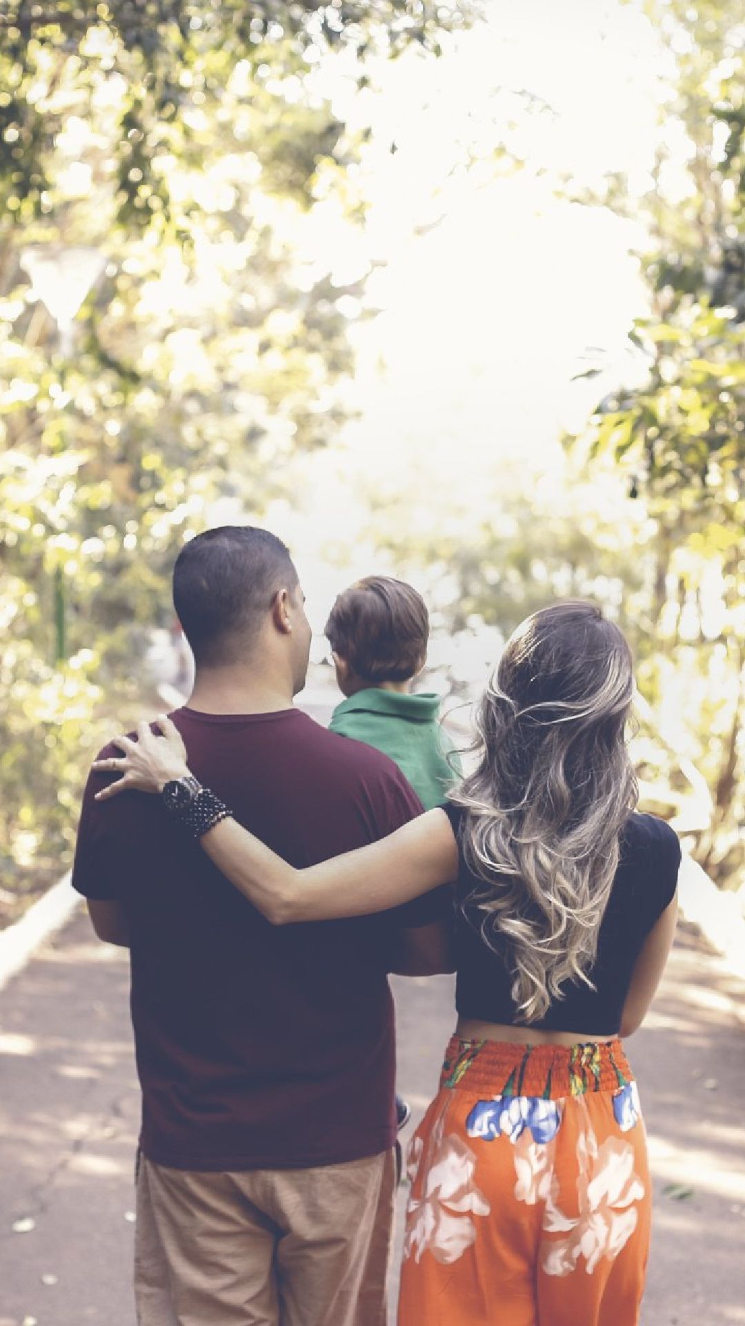 A man and a woman are walking with a child in their arms.