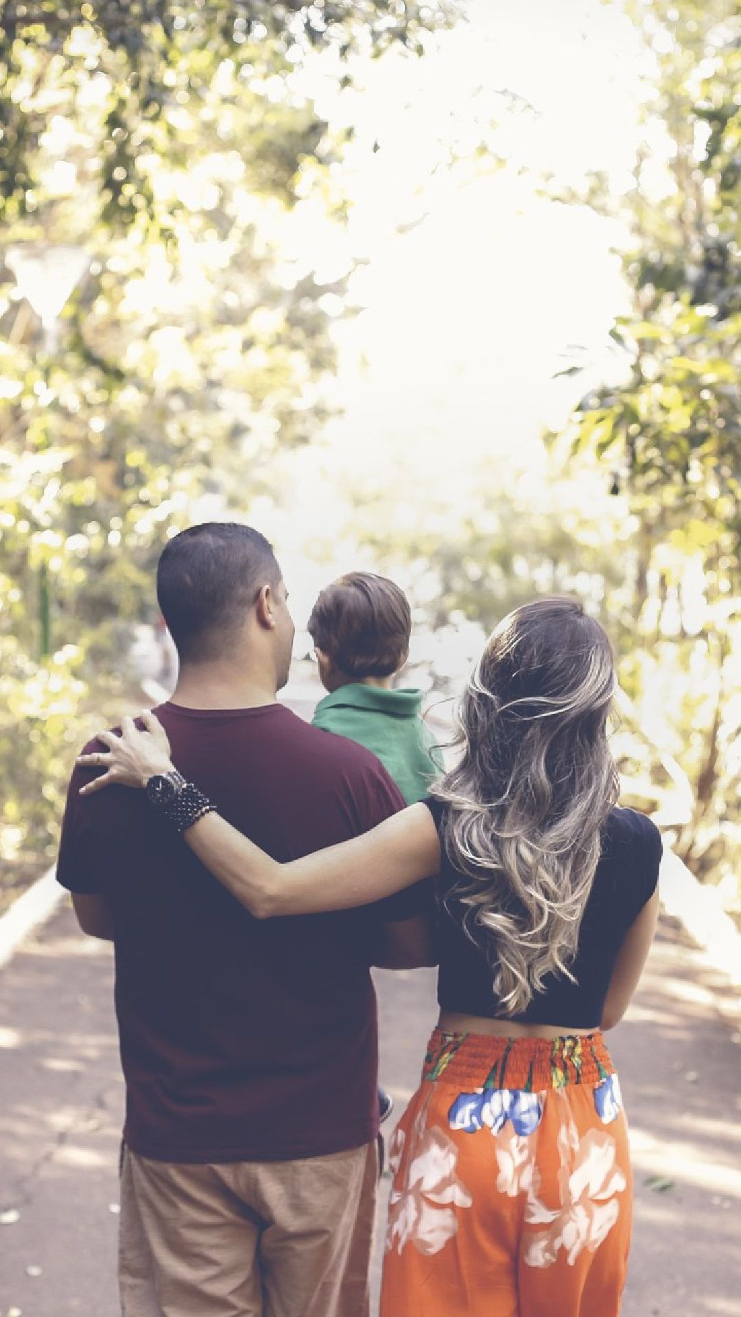 A man and a woman are walking down a road with a child.