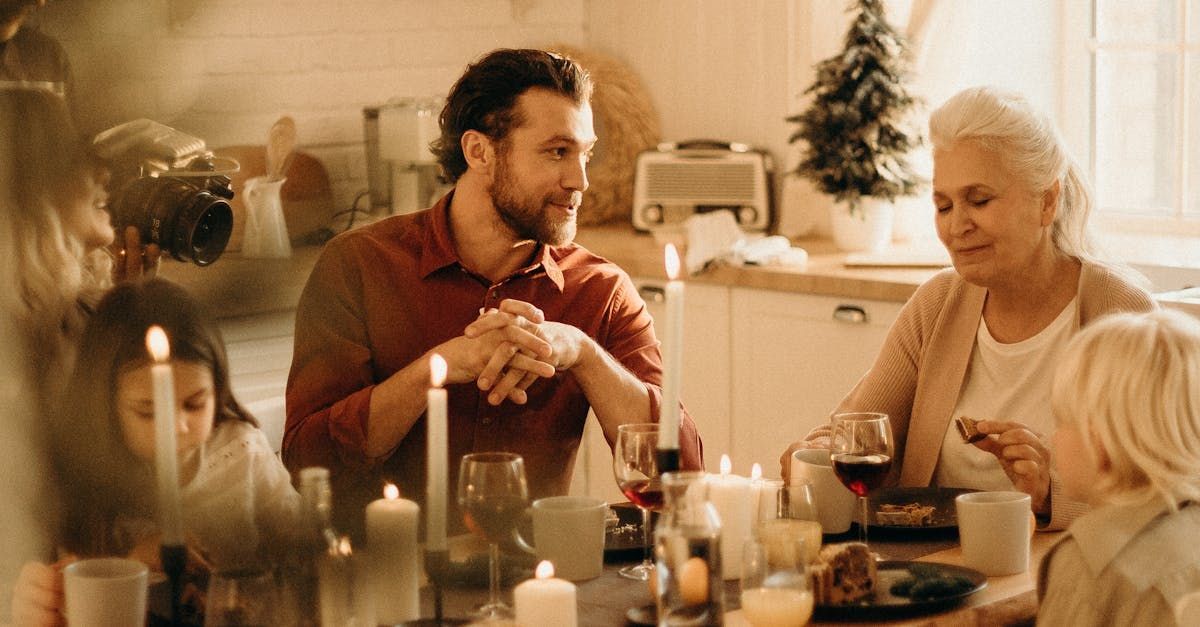 A family is sitting at a table with candles and wine glasses.