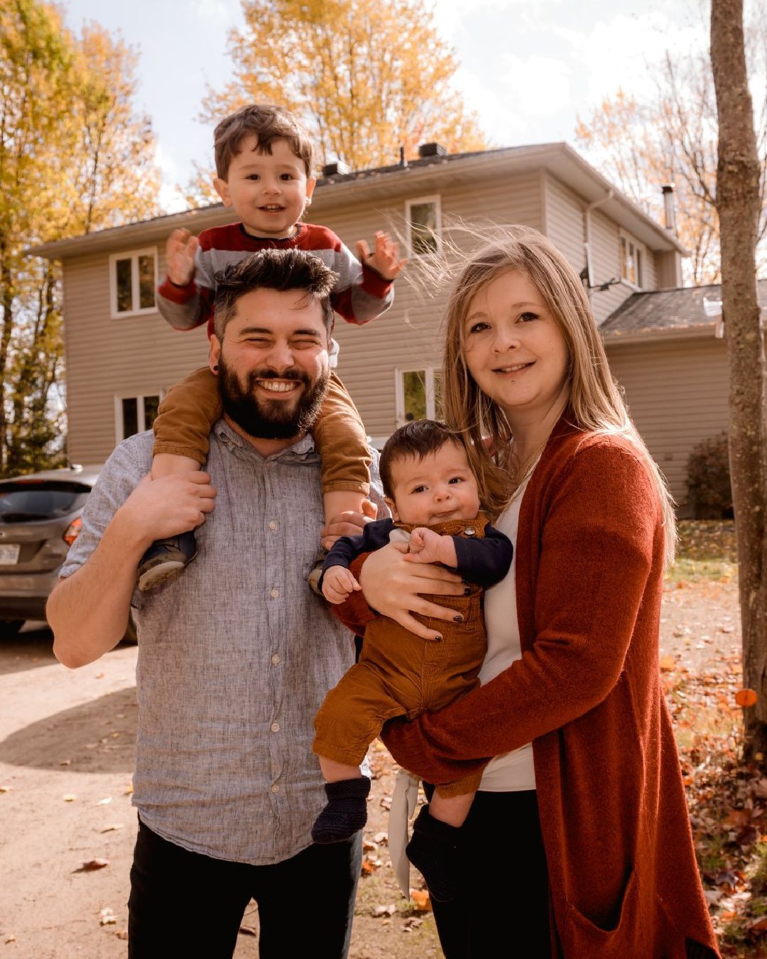 A family is posing for a picture in front of a house.
