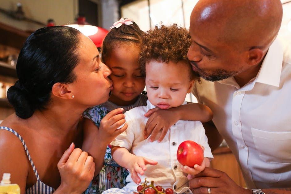 A man and woman are kissing a baby on the cheek.