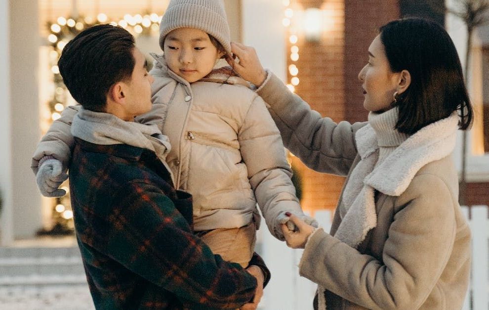 A man and a woman are holding a little girl in their arms.