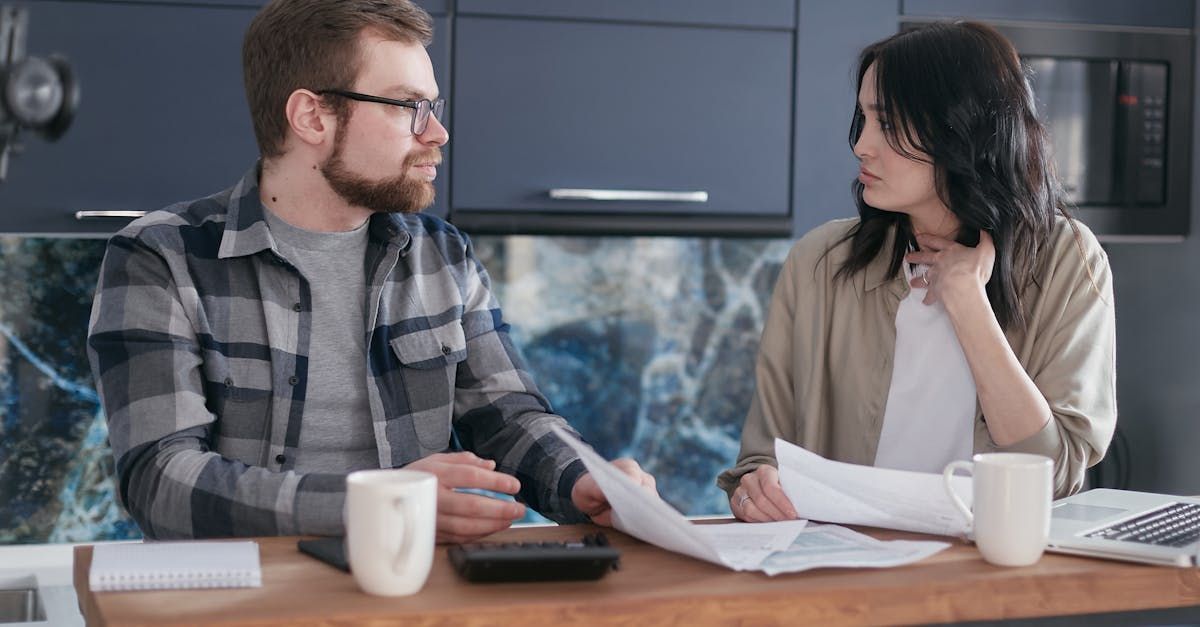 A man and a woman are sitting at a table looking at papers.
