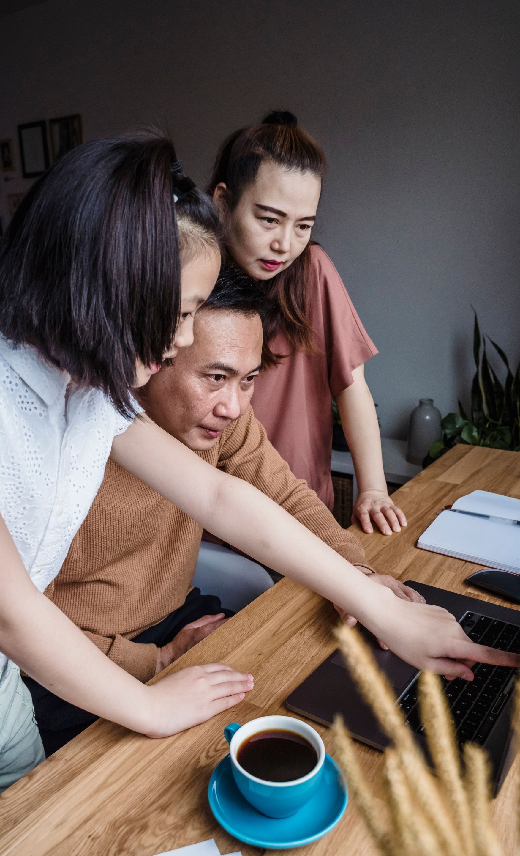 A group of people are sitting at a table looking at a laptop computer.
