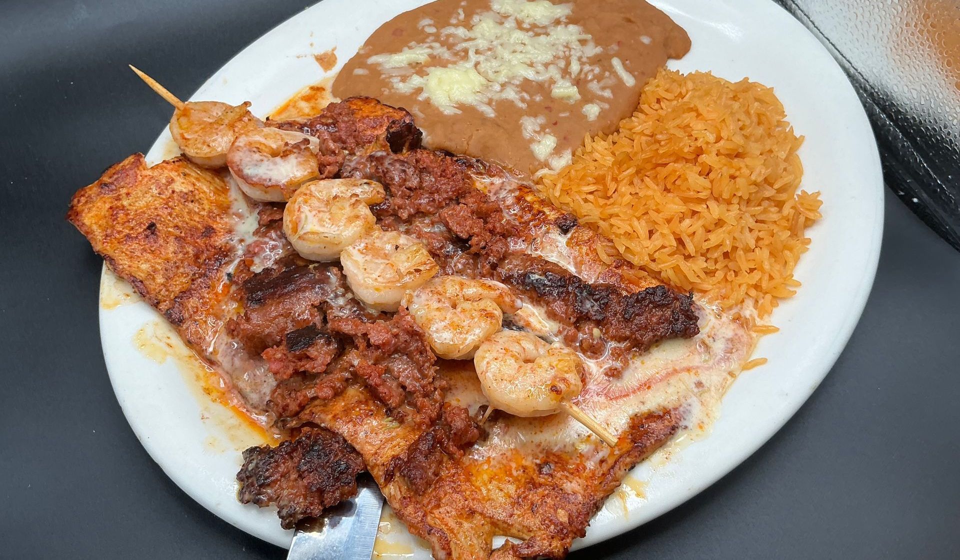 Grilled seafood dish with rice and beans on a white plate.