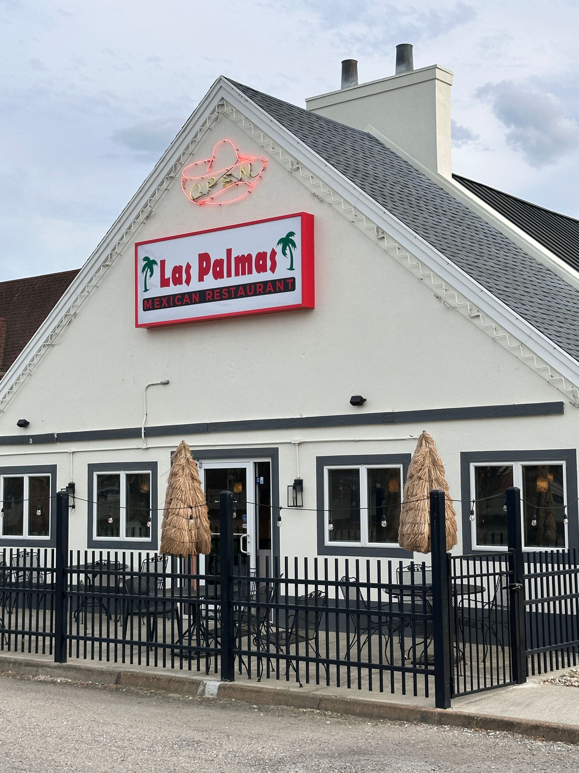 La Palmar restaurant exterior with sign, white facade, black railing, outdoor seating.