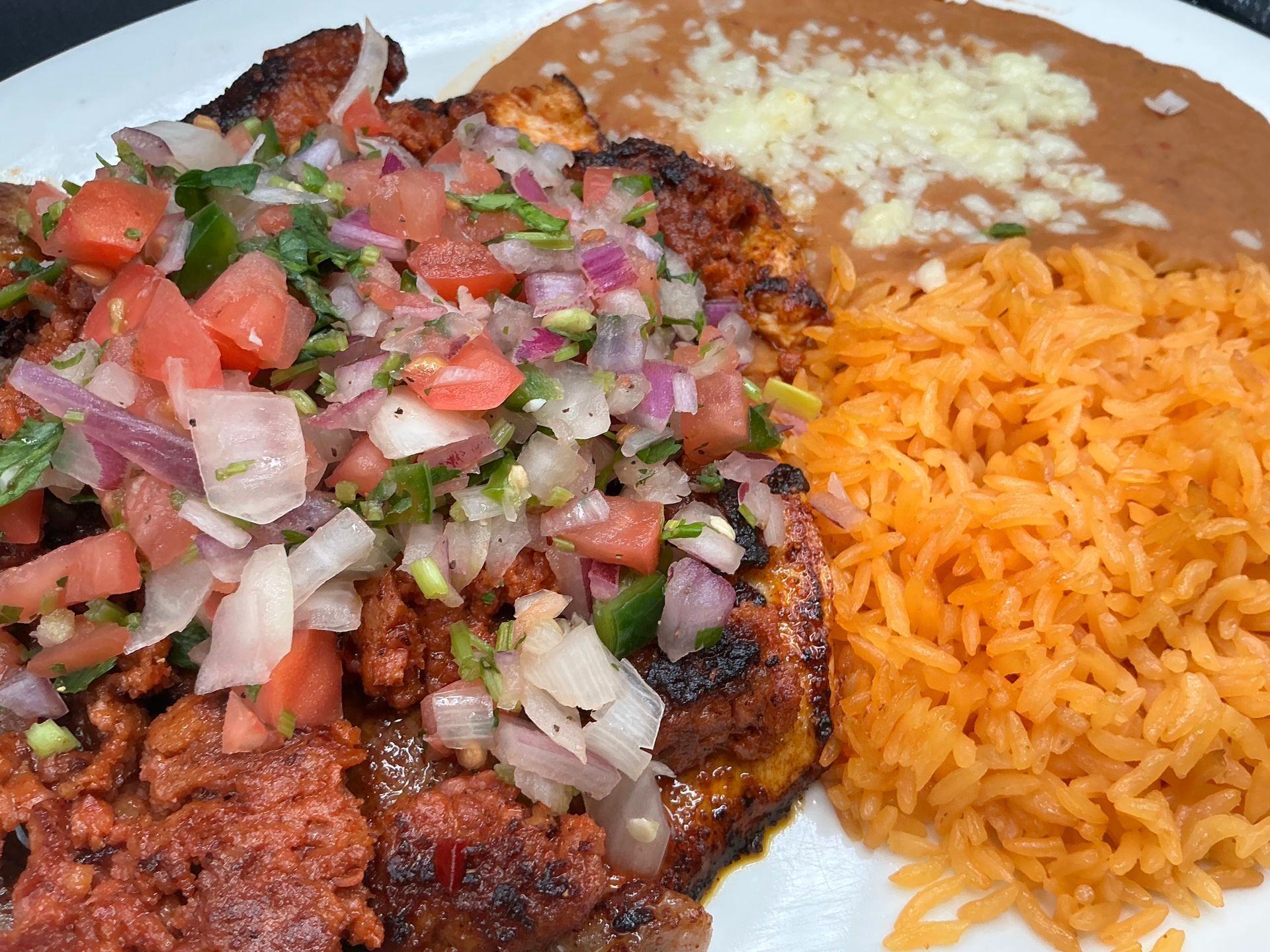 Grilled chicken topped with pico de gallo, refried beans with cheese, and Mexican rice.