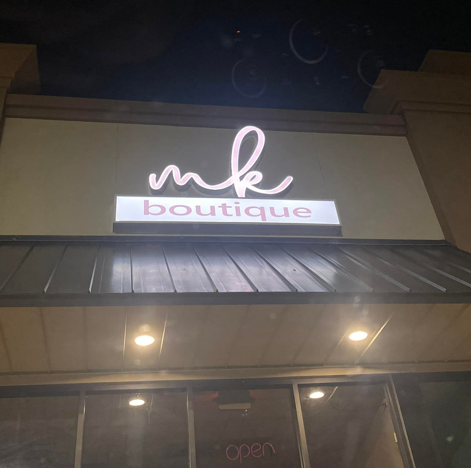 MK Boutique storefront with illuminated sign.