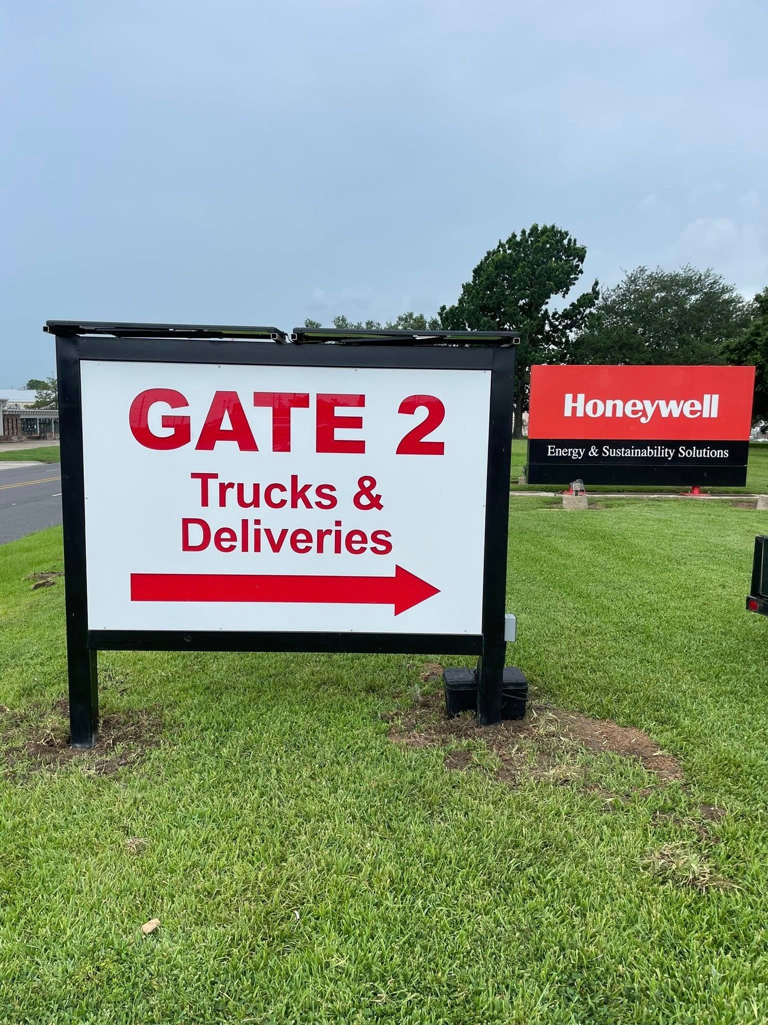 Sign for Gate 2, Trucks & Deliveries. Arrow points right. Honeywell sign in background.