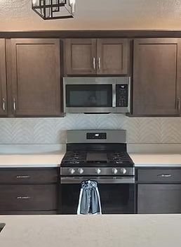 Modern kitchen with dark cabinets, stainless steel appliances, and a towel on the oven handle