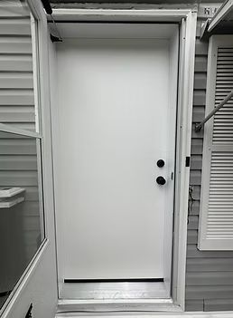 White exterior door with black knob and sidelight windows on a gray house porch