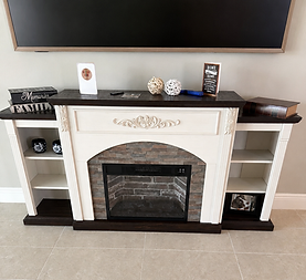 White fireplace mantel with shelves, black TV above, and decorative accents in a living room