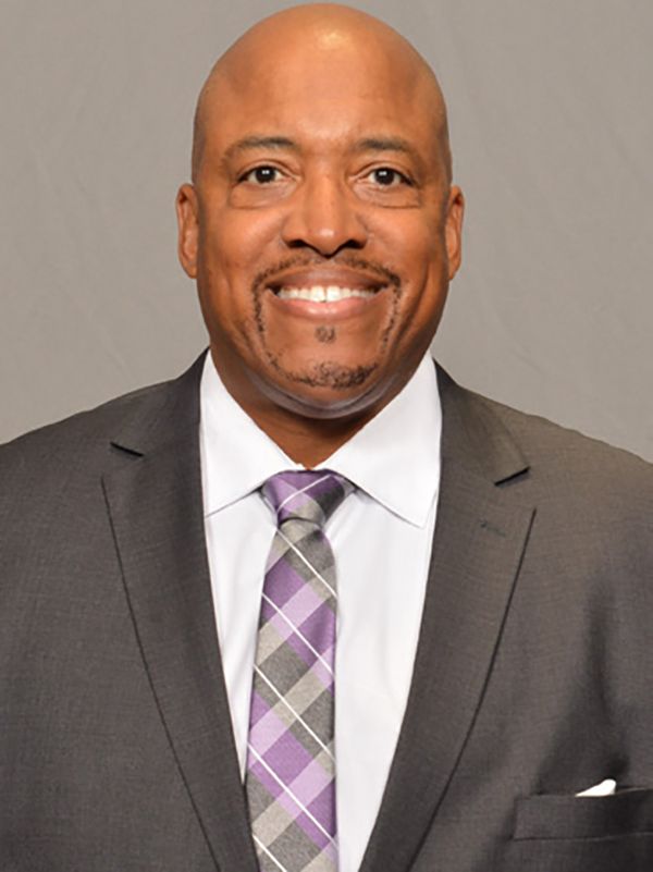 A man in a suit and tie is smiling for the camera. It's Coach Gholson.